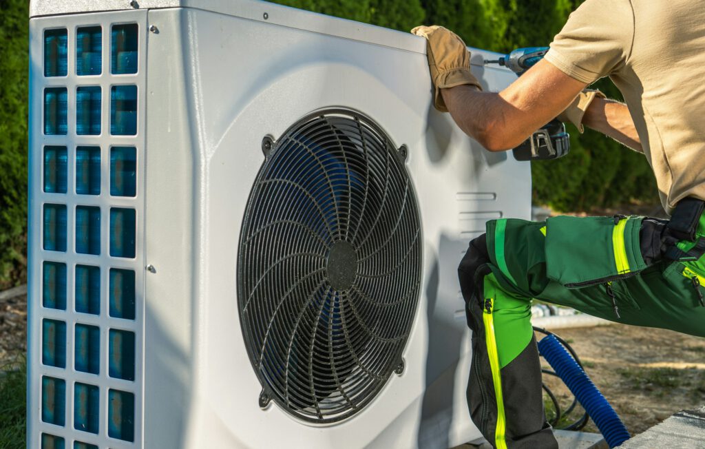 Heizungsbauer arbeitet an einer Außeneinheit einer Wärmepumpe